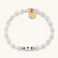 Pearl bracelet with a gold tag and 'ATX' beads on a white background