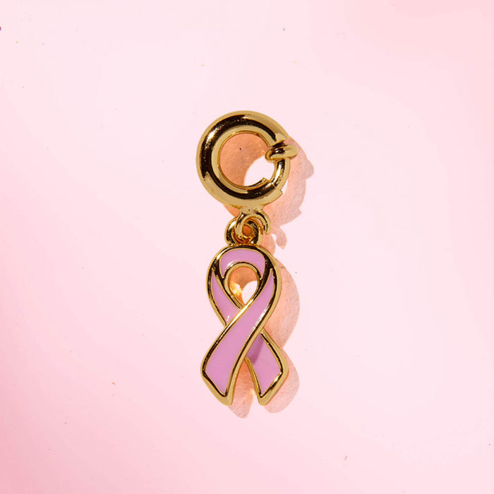 Pink ribbon charm with gold accents on a pink background
