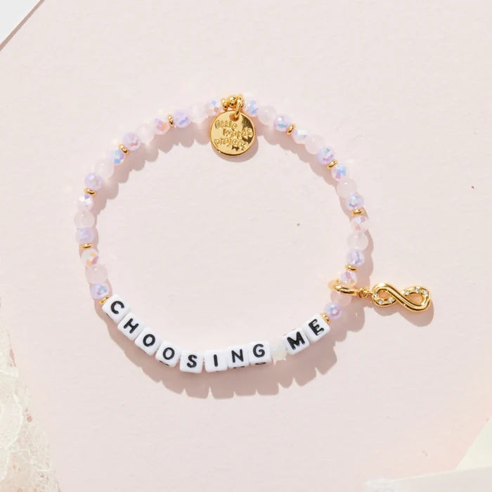 Bracelet with letter beads spelling 'CHOOSING ME' on a light pink background