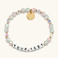 Personalized beaded bracelet with 'YOUR TEXT' on a white background