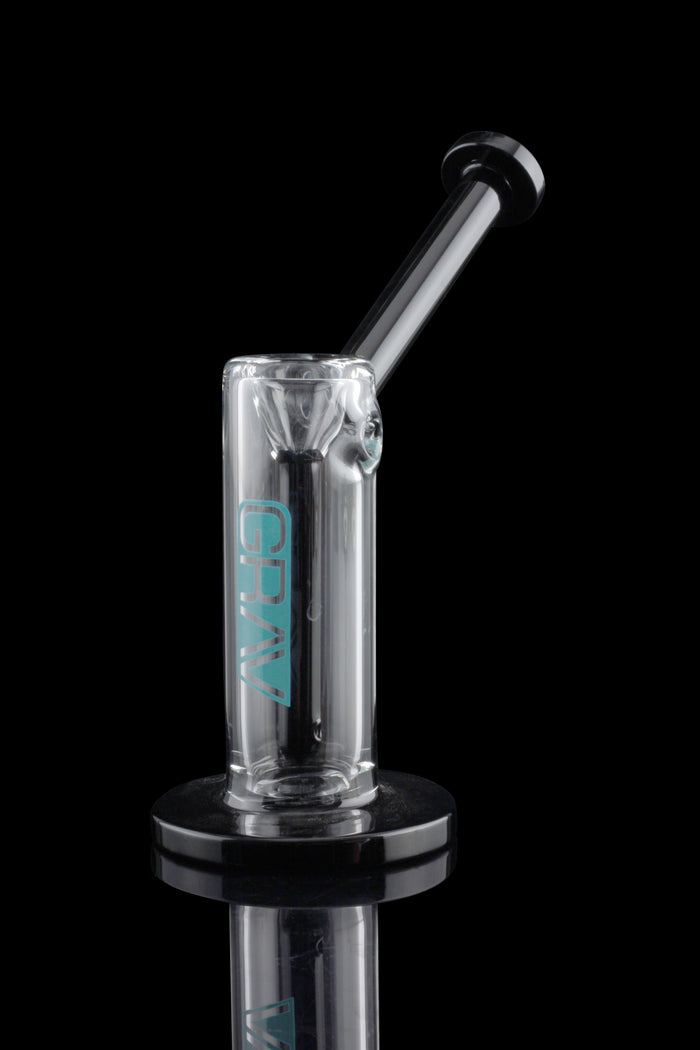 Clear glass oil rig with turquoise lettering, displayed on a black stand with a reflective surface.