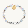 Lucky 13 bracelet flat-lay with frosted light-blue and iridescent clear beads, silver crystal accents, gold spacers, and a gold Little Words Project charm