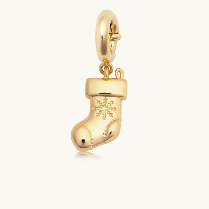 Gold bag charm shaped like a Christmas stocking with a snowflake design on a white background