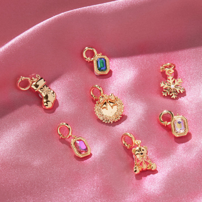 Gold charms with colorful gemstones on a pink satin background