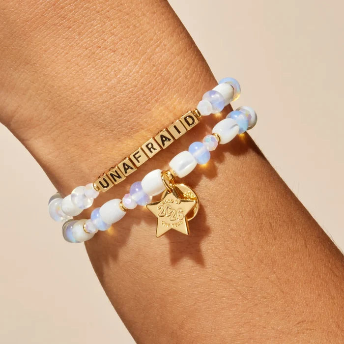 Bracelet with 'UNAFRAID' on a wrist against a beige background