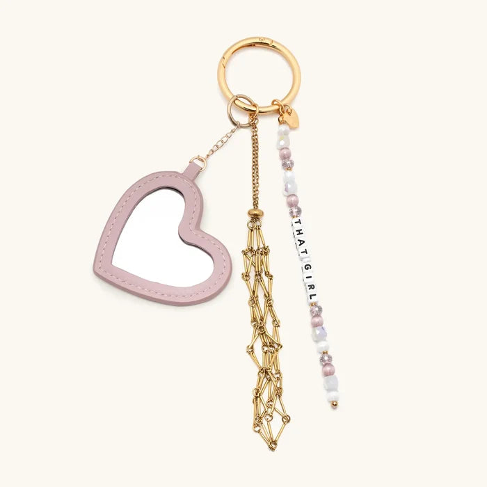 Keychain with heart-shaped charm, gold tassel, and beaded tag on a white background